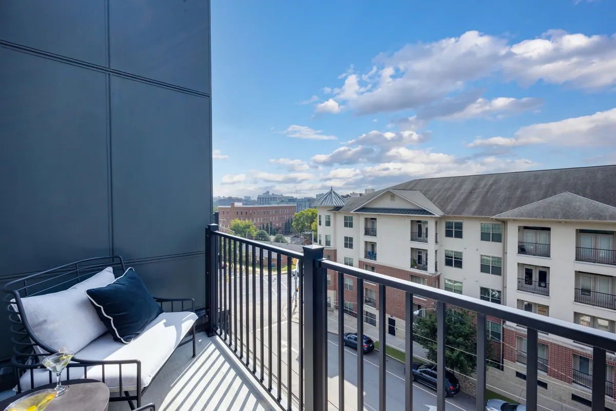 An inviting exterior balcony scene with seating overlooking the city skyline under a soft, cloudy sky. The setting suggests a relaxing spot to unwind after a day of adventure, with space for families or friends to gather and enjoy outdoor moments together.